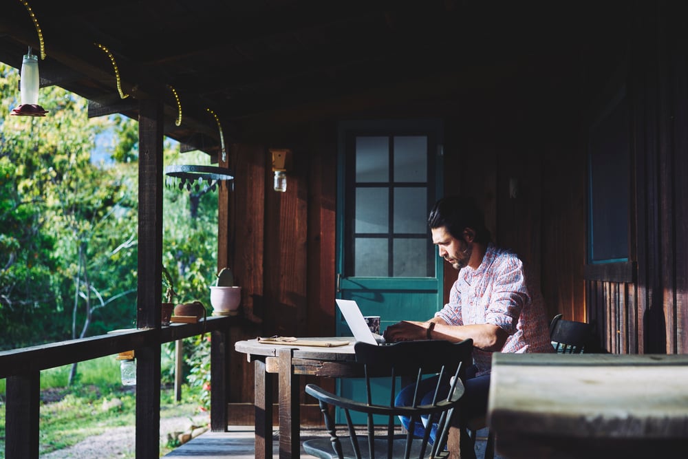 Mid adult man using laptop on verandah