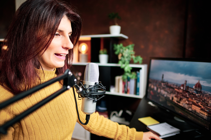 Woman podcasting at home with microphone and computers